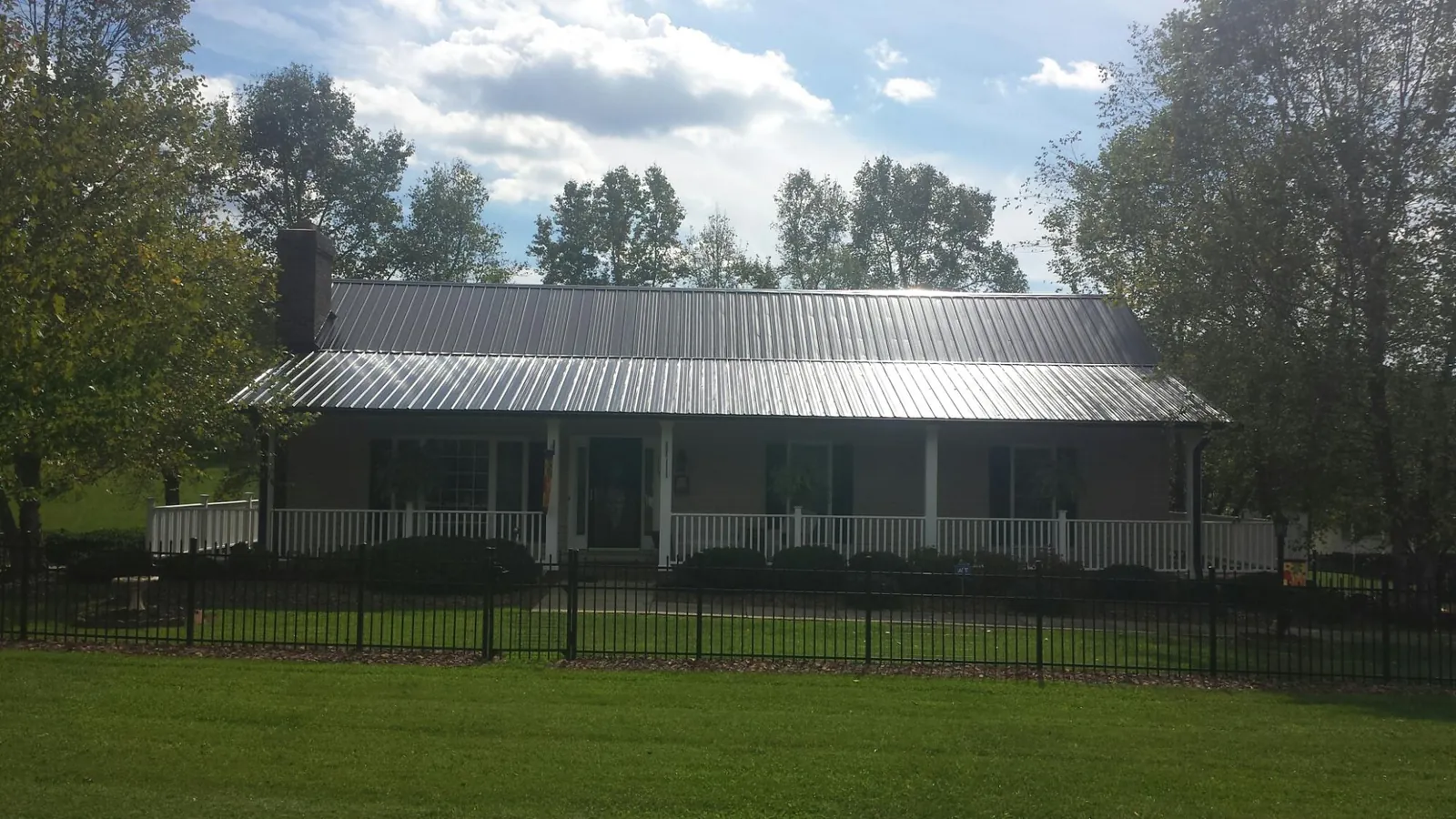 Gray metal roof on a brick ranch with a full width front porch — Gutter Guard Installation work by our crew in Hadley