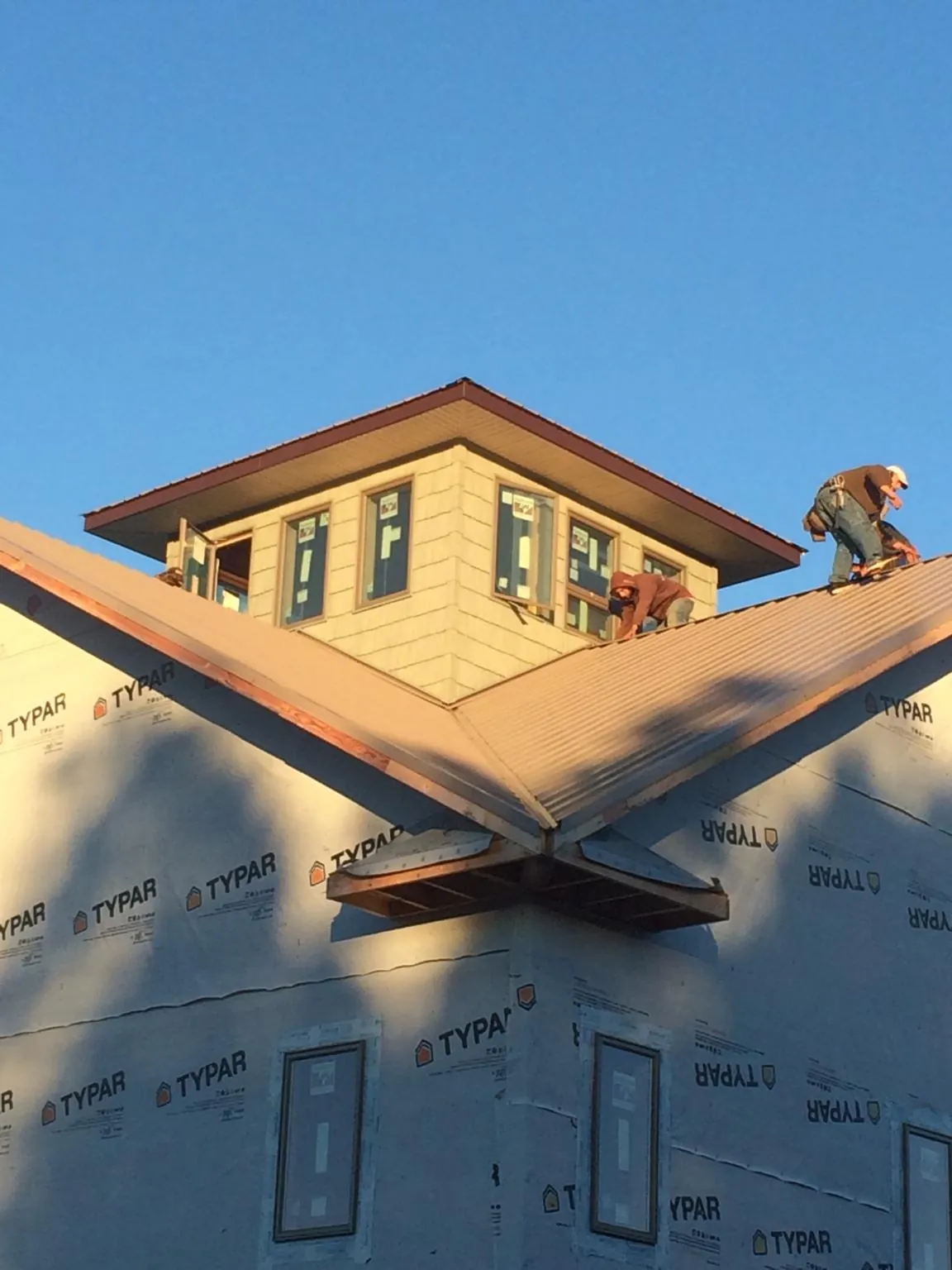 Roofers working around a rooftop cupola on a new metal roof at sunset — Roof Waterproofing in Hadley by Roofing Brothers